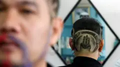Mitree Chitinunda, a former ultra-royalist, getting the three-fingers salute cut into his hair - a symbol of anti-government protest that is demanding curb for monarchy's power in Bangkok, Thailand