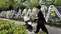 9일 서울 용산구 용산어린이정원 입구에 정부의 용산공원 부지 주택 공급 검토에 반대하는 근조화환들이 줄지어 세워져 있다. 화환 앞으로 검은 유모차를 끌고 가는 한 남성이 보인다.