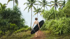 surfer carries longboard 