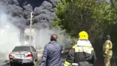 мужчина в куртке и спасатель смотрят на густой дым