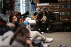 Passageiros sentados aguardam informações sobre seus voos no aeroporto de Maiquetía