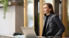 Kobieta z biura zaufania siedzi przy ladzie recepcyjnej i pracuje z laptopem - zdjęcie stockowe