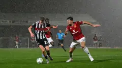 Yağmur altında top koşturan futbolcular