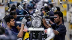 دو کارگر در یک کارخانه در چنای هند موتورسیکلت مونتاژ می‌کنند