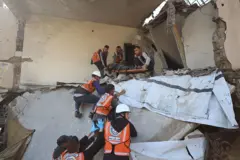 تظهر في الصورة فرق طبية تنتشل جثة أحد الأشخاص الذي لقي مصرعه، بعد انهيار مبنى بسبب الأمطار الغزيرة، في حي النصر بقطاع غزة، في 16 ديسمبر/كانون الأول عام 2025. ويرتدي بعض من المنقذين خوذة رأس وسترة كُتب على ظهرها "الدفاع المدني".