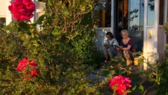 a mother and daughter read their books on the steps of their home