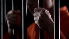 Recluso agarrando los barrotes de una celda.