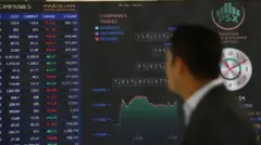 صورة لرجل ينظر إلى شاشة تبيّن أسعار الأسهم في البورصة الباكستانية.