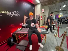 Homem sentado em mesa expondo antebraço com tatuagem