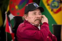 Daniel Ortega usa um boné preto e uma jaqueta vermelha