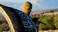 Suriye'de yüzü kapalı, elinde dini bir bayrak olan, İslamcı bir militan