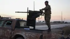 Esad'a muhalif bir savaşçı tankın üzerinde silah tutuyor, 2 Aralık 2025, Halep 