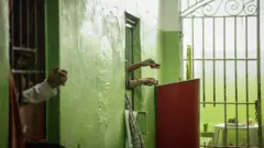 Inmates use mirrors to view visitors from their cells in the aging Desembargador Raimundo Vidal Pessoa penitentiary, inaugurated in 1904, on February 17, 2016 in Manaus, Brazil.