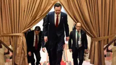 Üç takım elbiseli adam merdivenleri çıkıyor. Çıktıkları merdivenlerde büyük bir perde de var. Bu perdenin arasından geçiyorlar.