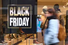 Mulher passa em frente a vitrine com uma placa de Black Friday