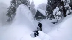 A Running Springs, California resident clears snow outside his home