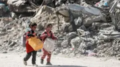 gazze'de yıkıntılar arasında yürüyen iki çocuk