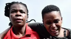 Umugore uhangayitse cyane urimo gufashwa n'umukozi wa Croix-Rouge yo muri Uganda 