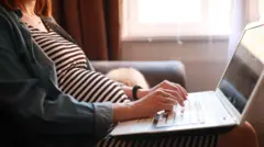 Jovem grávida usando um laptop apoiado no colo