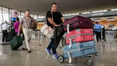 チャール・クラインハウスは空港に到着し、3つの非常に大きなスーツケースで車を押します。