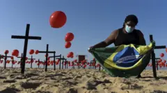Un homme tient le drapeau brésilien entre des ballons rouges à Rio de Janeiro
