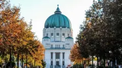 Imagem de um prédio central em uma rua com árvores