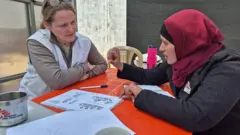 Katrin e um colega da equipe local da MSF estão planejando um workshop. Eles estão sentados à mesa conversando.
