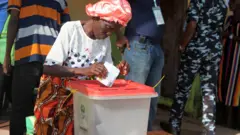 Obìnrin tó ń fi ìbò rẹ̀ sínú àpótí ìbò