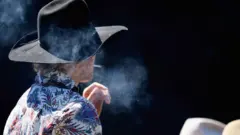 Sigara içen kovboy şapkalı kişi