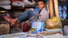 በሸቀጥ ሱቅ የተቀመጠ ታዳጊ 