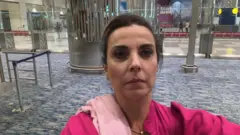 Marilu no aeroporto, com olhar sério