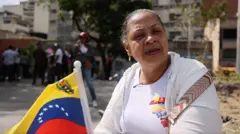 Una mujer sostiene una bandera de Venezuela. Detrás se ve gente en las calles.