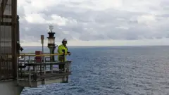 Homem observa o horizonte em uma plataforma em alto-mar