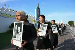 .Members of the public, dressed in mourning attire, queue patiently to participate in the ritual of offering condolence water (Nam Song Phra Borom Soph) before the royal portrait of the late Her Majesty Queen Sirikit The Queen Mother at Sahathai Samakhom Hall, located within the Grand Palace, on Suday, October 26, 2025.