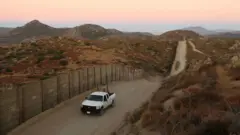 Un vehículo de la patrulla policial circula cerca del muro que divide la frontera entre México y EE.UU.