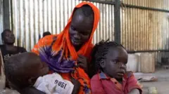 Sarah Williams, with an orange headscarf, sitting with two of her children in her lap