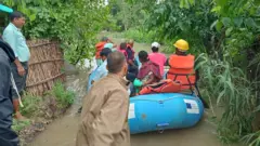 कैलालीको टीकापुरमा बाढीले जलमग्न घरबाट पीडितहरूलाई उद्धार गरिँदै 