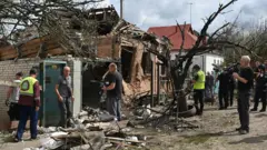 Uma casa destruída por um ataque aéreo russo na Ucrânia. Pessoas estão ao redor do imóvel em ruínas