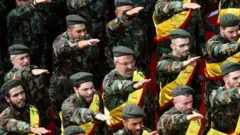 اعضای جنبش شیعه حزب‌الله لبنان در مراسم تشییع جنازه سه تن از همرزمانشان که در جنگ سوریه کشته شده‌اند، در شهر نبطیه در جنوب لبنان، در ۸ نوامبر ۲۰۱۷، پشت تابوت‌های آنها ادای احترام می‌کنند.