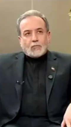 ඉරාන විදේශ අමාත්‍ය අබ්බාස් අරග්චිගේ ෆොටෝ එකක් මෙහි දැක්වෙන අතර ඔහු කළු පාට කොට එකකින් සැරසි සිටි.