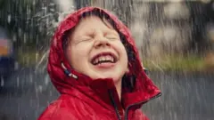 Criançacasa de apostas presidente do brasilcasaco vermelho com capuz sorrindo enquanto toma chuva 