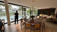Agente da polícia federal está de costas em sala de jantar de casa de luxo alvo da operação contra lavagem de dinheiro em postos de combustíveis