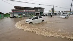 A vehicle makes its way along a waterlogged road following flooding caused by heavy rain in Cheongju, South Korea