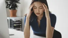 Woman suffering from headache in front of a laptop