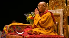 O 14º Dalai Lama, sentado com as mãos postas