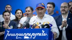 Нікол Пашинян у колі своїх прихильників, стоїть за трибуною, у блейзері кольорів національного прапора Вірменії 
