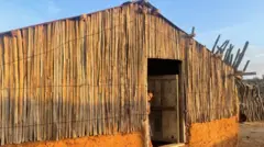 Mulher olha pela porta de uma casa tradicional de barro e cacto no norte da Colômbia