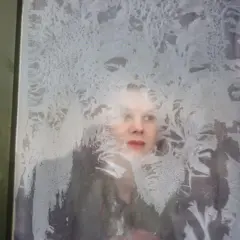 Uma mulher olhando através de uma janela embaçada pela condensação