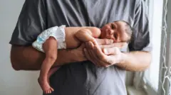 رجل يحمل على ذراعه طفل صغير 