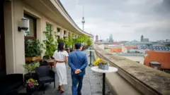 Obinrin to wọ aṣọ funfun ati ọkunrin to wọ kootu olomi buluu n kọwọọ rin lọ
